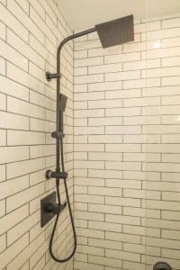 Black rainfall shower with handheld sprayer against white subway tile